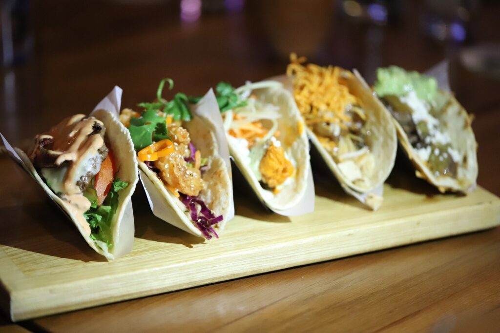 A wooden board with several tacos on it.