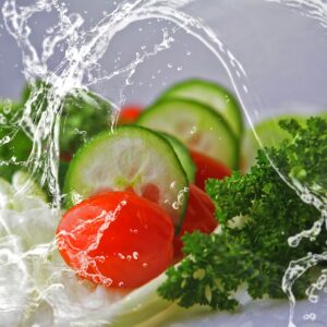 A plate of vegetables being splashed with water.