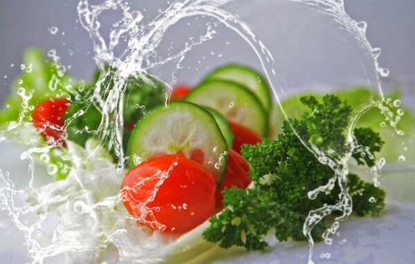 A plate of vegetables being splashed with water.