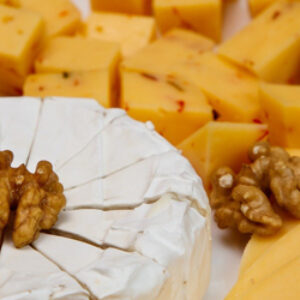 A cheese platter with nuts and cheeses on the side.