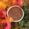 A cup of coffee sitting on top of some pomegranates.